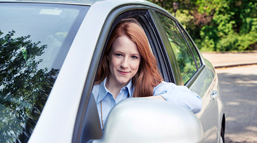 a woman sitting in a car's driver seat - Free Insurance Quotes